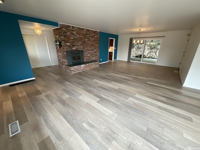 unfurnished living room featuring wood finished floors, visible vents, and an inviting chandelier