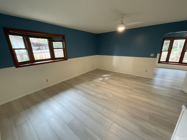 unfurnished room with light wood-style flooring, arched walkways, and ceiling fan