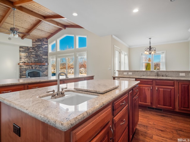 kitchen featuring vaulted ceiling with beams, a stone fireplace, a sink, and dark wood finished floors