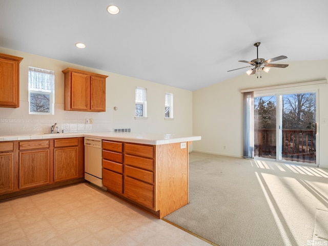 kitchen featuring lofted ceiling, white dishwasher, recessed lighting, a peninsula, and brown cabinets