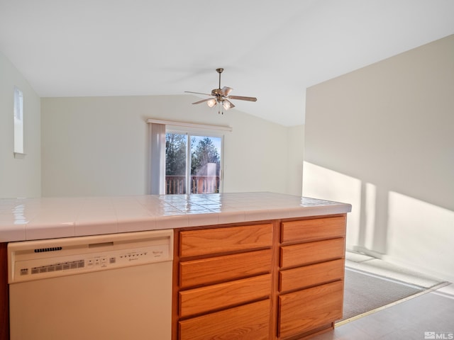 kitchen featuring a ceiling fan, lofted ceiling, white dishwasher, and tile countertops