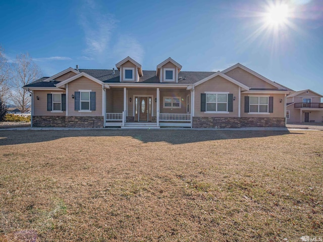 view of front of house featuring stone siding, a porch, and a front lawn