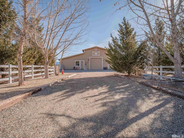 exterior space featuring an outbuilding, gravel driveway, fence, and a garage