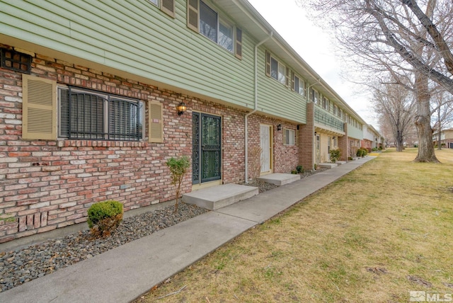 exterior space with a lawn and brick siding