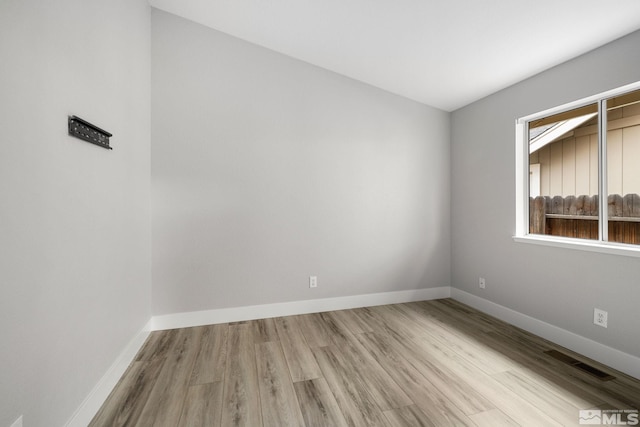 empty room featuring wood finished floors, visible vents, and baseboards