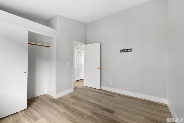 unfurnished bedroom featuring a closet, light wood-type flooring, and baseboards