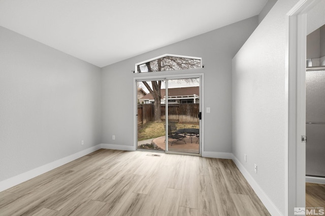 empty room featuring baseboards, vaulted ceiling, and light wood finished floors