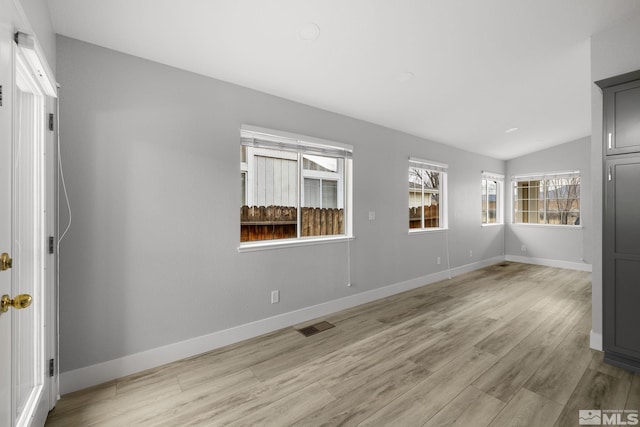 spare room with light wood-style floors, visible vents, vaulted ceiling, and baseboards