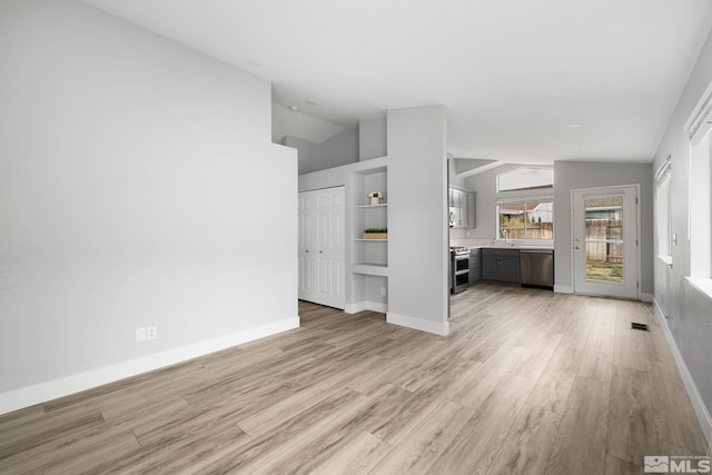 unfurnished living room featuring lofted ceiling, baseboards, and light wood finished floors