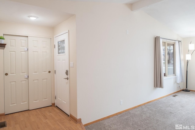 entrance foyer featuring vaulted ceiling with beams, light wood-style floors, visible vents, and baseboards