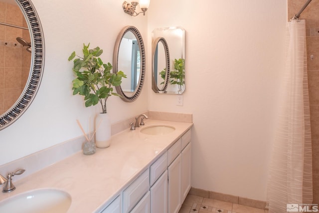 full bath with a tile shower, tile patterned flooring, a sink, and baseboards