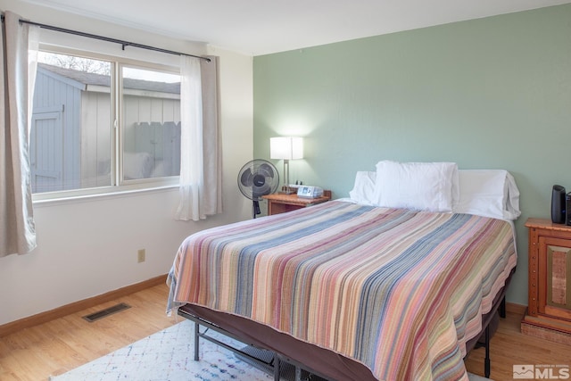 bedroom featuring visible vents, baseboards, and wood finished floors