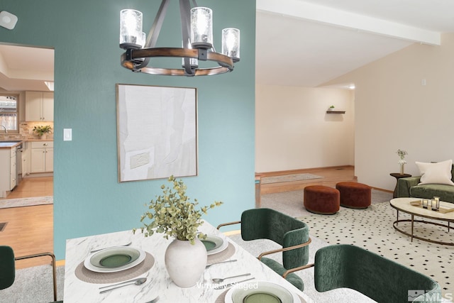 dining room featuring light wood-type flooring, lofted ceiling with beams, baseboards, and an inviting chandelier