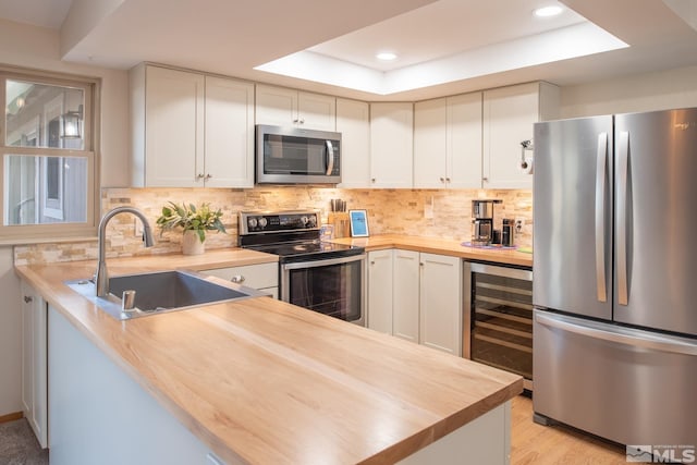 kitchen featuring butcher block counters, wine cooler, stainless steel appliances, and a sink