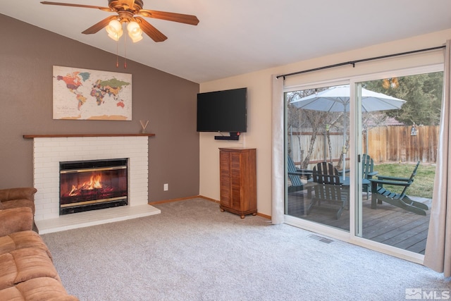 carpeted living area with visible vents, a brick fireplace, vaulted ceiling, ceiling fan, and baseboards