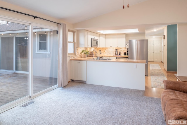 kitchen featuring visible vents, appliances with stainless steel finishes, open floor plan, white cabinets, and a peninsula