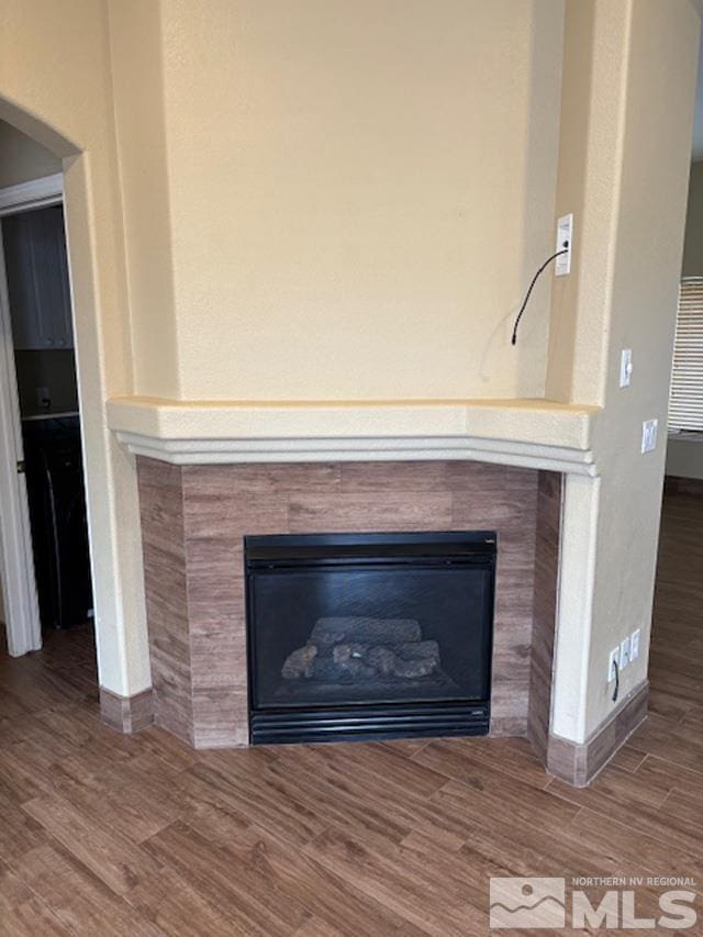 interior details featuring baseboards, a tiled fireplace, and wood finished floors