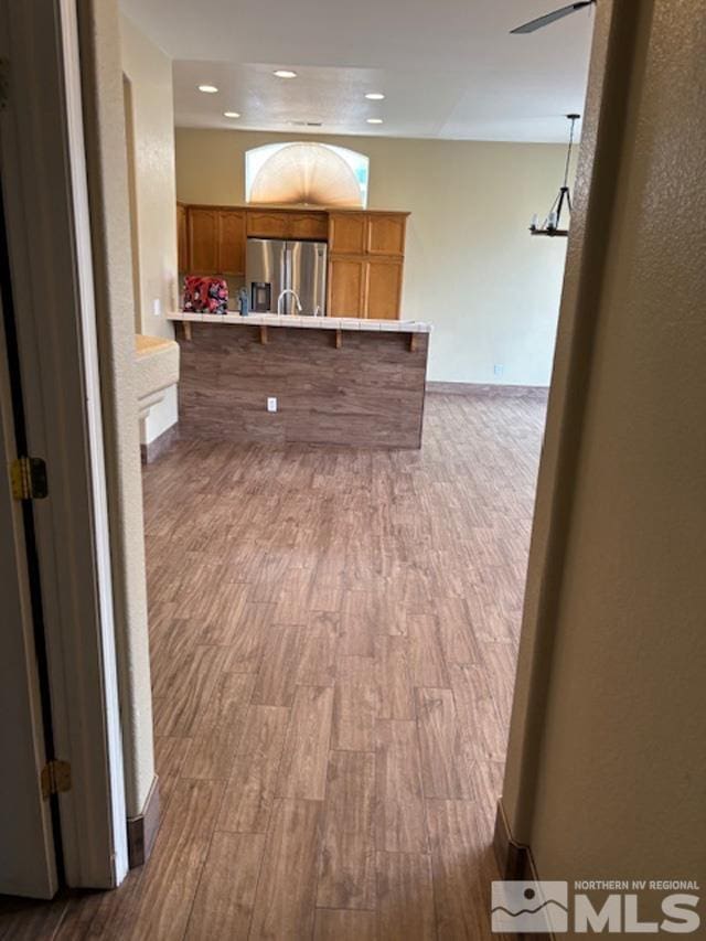 interior space featuring a ceiling fan, recessed lighting, baseboards, and wood finished floors