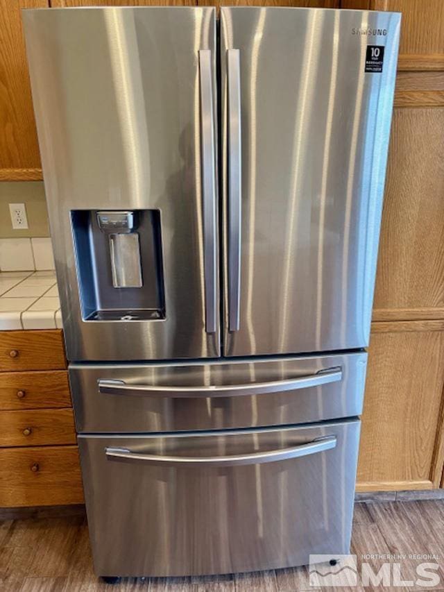 room details featuring wood finished floors, stainless steel refrigerator with ice dispenser, and tile countertops