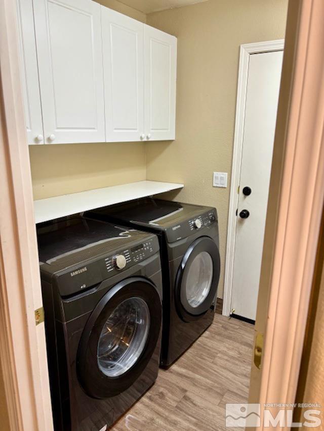 washroom featuring cabinet space, light wood-style flooring, and washer and dryer