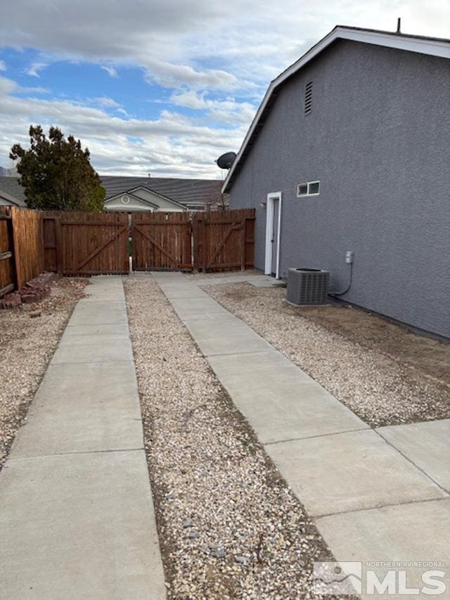 view of yard with a gate, fence, and central AC