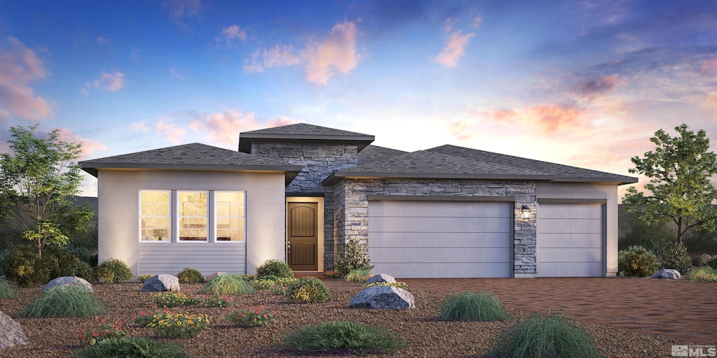 prairie-style home with an attached garage, stone siding, and decorative driveway