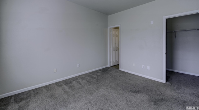 unfurnished bedroom featuring a closet, carpet flooring, a walk in closet, and baseboards