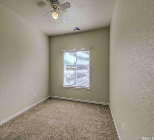 empty room featuring a ceiling fan, carpet, visible vents, and baseboards