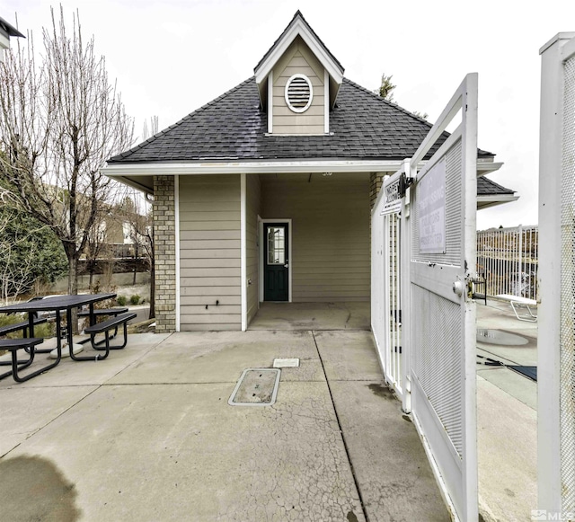 exterior space featuring outdoor dining area, roof with shingles, a patio area, and fence