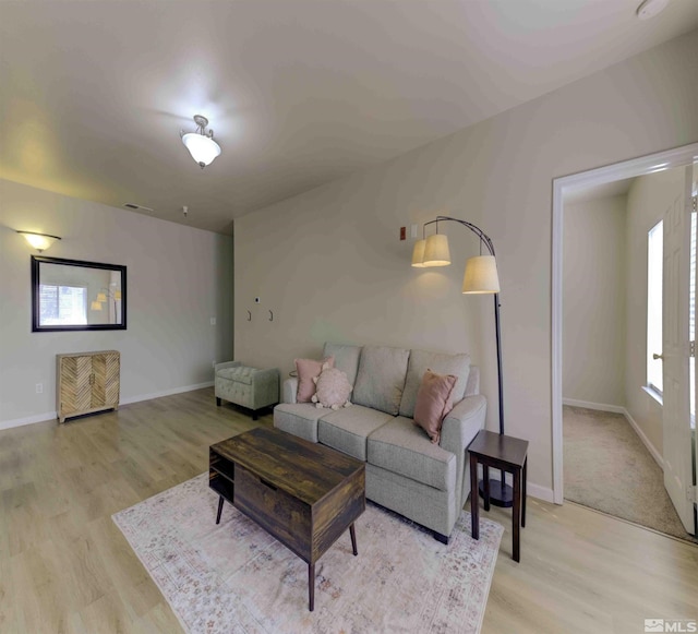 living area with light wood-type flooring, visible vents, and baseboards