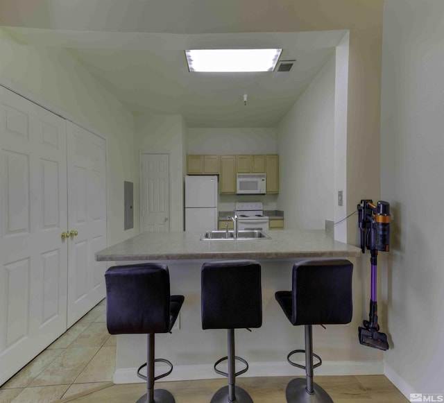 kitchen with a peninsula, white appliances, a breakfast bar, a sink, and visible vents