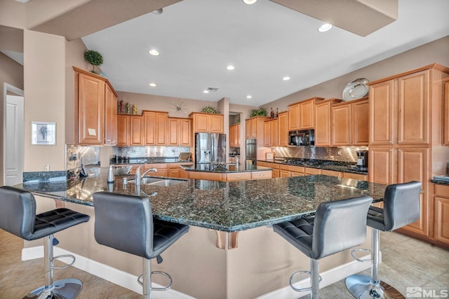 kitchen featuring tasteful backsplash, a sink, dark stone countertops, a peninsula, and black appliances