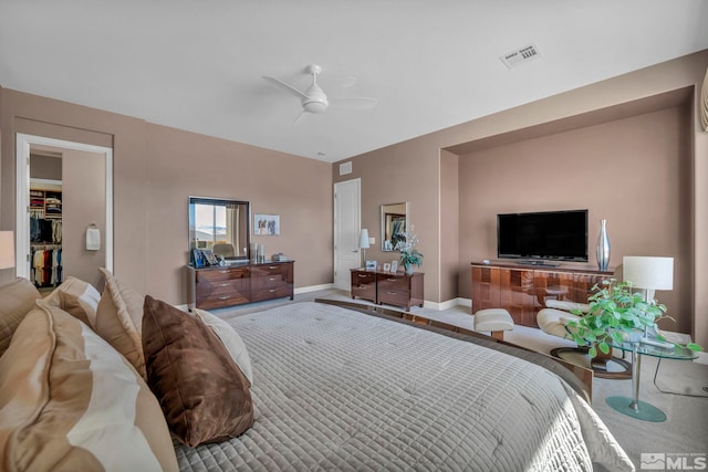 bedroom with baseboards, visible vents, a walk in closet, and a ceiling fan