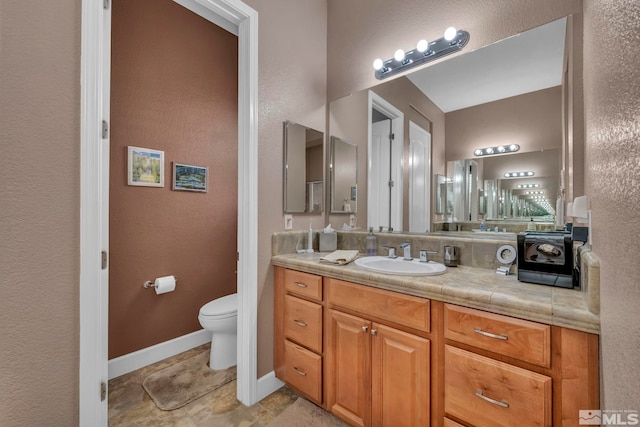 bathroom featuring baseboards, vanity, and toilet