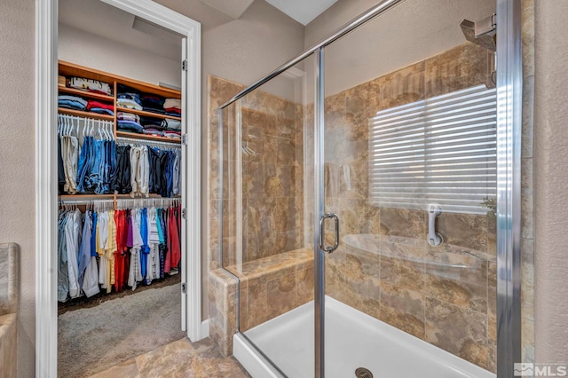 bathroom with a walk in closet and a shower stall