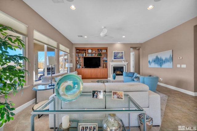 living room with built in shelves, recessed lighting, a glass covered fireplace, and baseboards