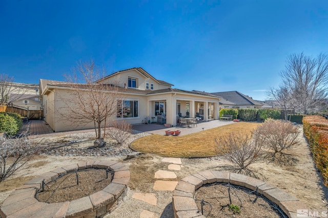 back of house with fence, a patio, and stucco siding