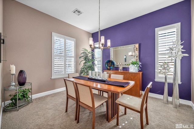 carpeted dining area featuring visible vents, a notable chandelier, and baseboards