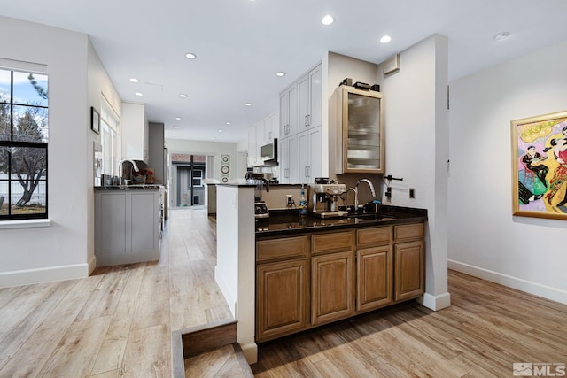 kitchen with light wood-type flooring, dark countertops, a sink, and recessed lighting