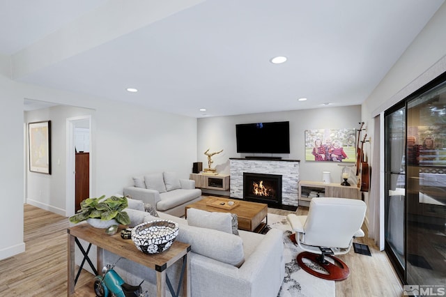 living area featuring light wood-type flooring, a fireplace, baseboards, and recessed lighting