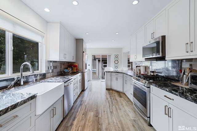 kitchen featuring stainless steel appliances, light wood finished floors, plenty of natural light, and a sink