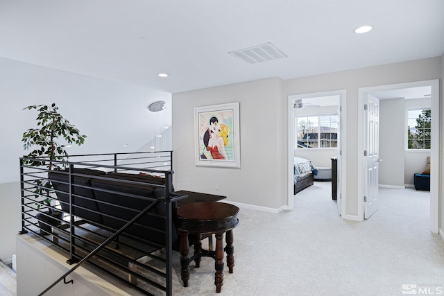 hallway with carpet floors, a wealth of natural light, visible vents, and baseboards