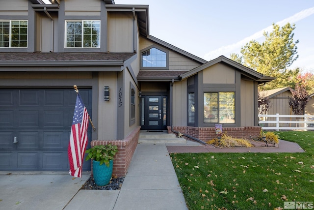 view of exterior entry with a garage, a yard, brick siding, and fence