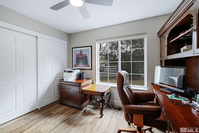 office space with light wood-style floors, ceiling fan, and baseboards