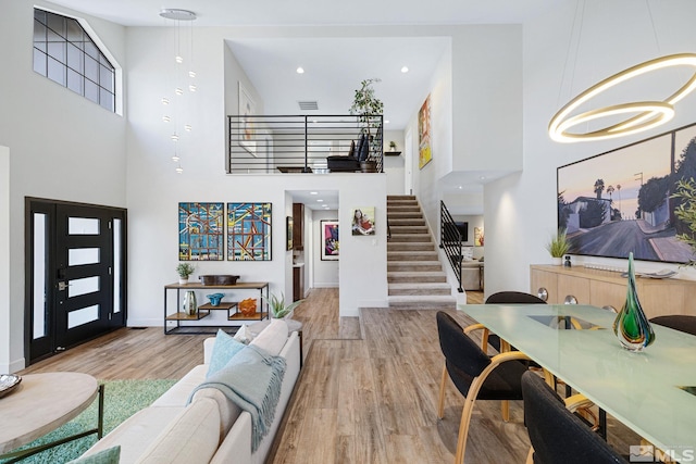 living area featuring stairs, a high ceiling, wood finished floors, and visible vents