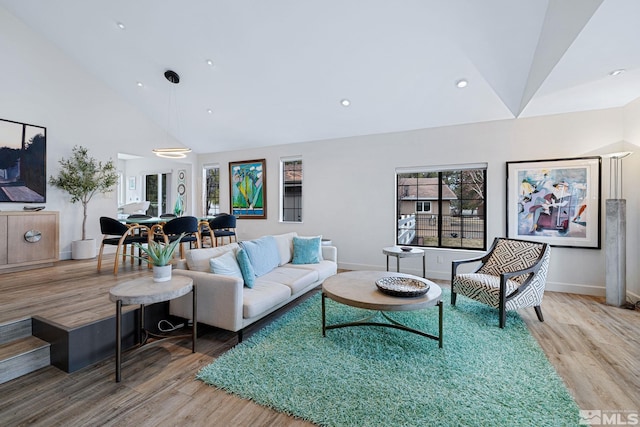 living room featuring high vaulted ceiling, recessed lighting, baseboards, and light wood finished floors