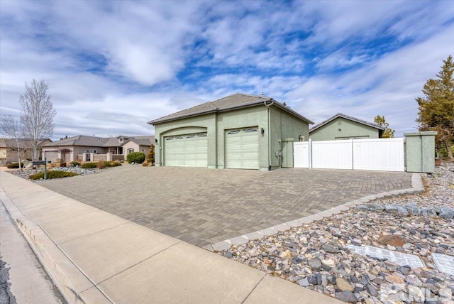 garage featuring a residential view, decorative driveway, and fence