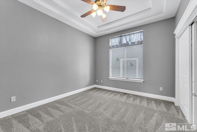 unfurnished bedroom featuring a raised ceiling, carpet flooring, and baseboards