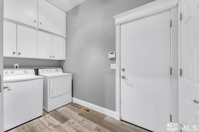 clothes washing area with cabinet space, visible vents, baseboards, washer and dryer, and light wood-style floors