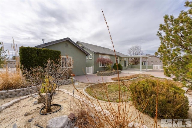 view of front of house featuring a patio, fence, and stucco siding